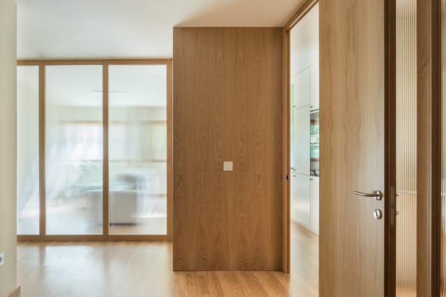 Oak-veneered volume beside reeded-glass doors that filter light from the living room.